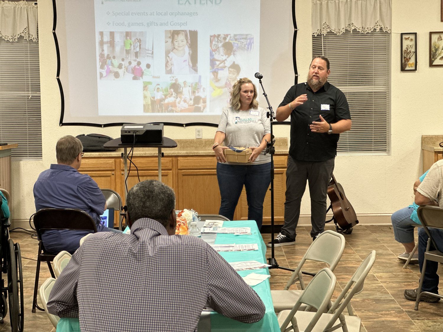Two speakers sharing about outreach events at orphanages