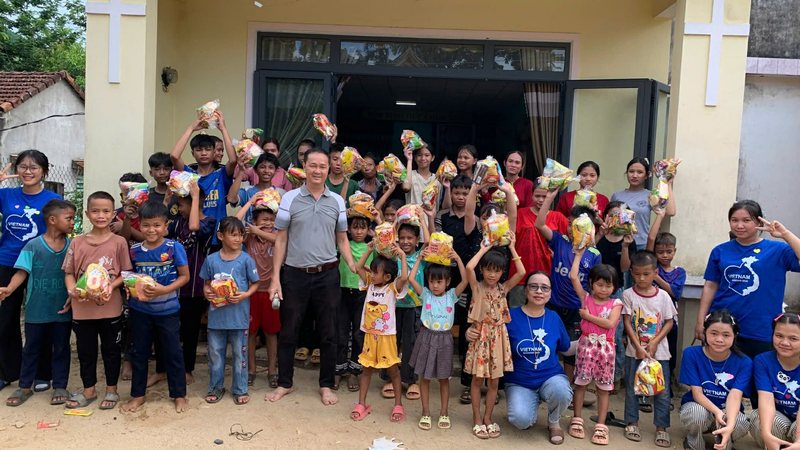 Children holding up snack bags outside a church with a visiting team