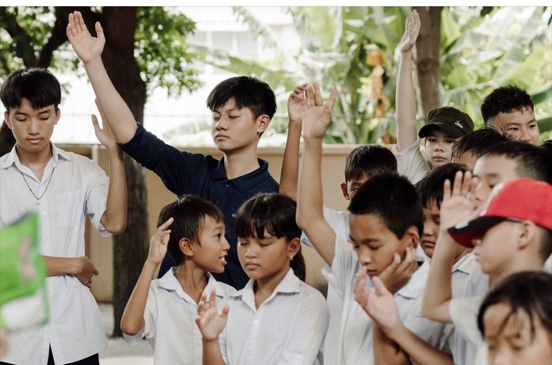 Young people praying outdoors with hands raised