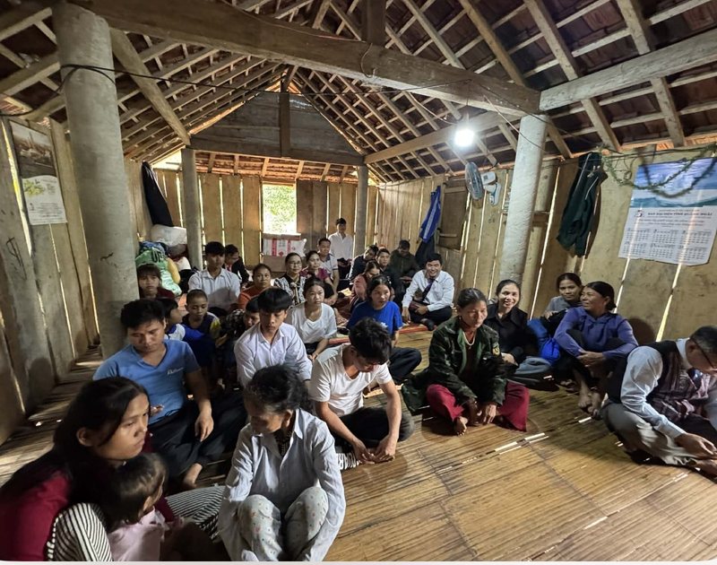 A congregation seated on the floor of a wooden house church