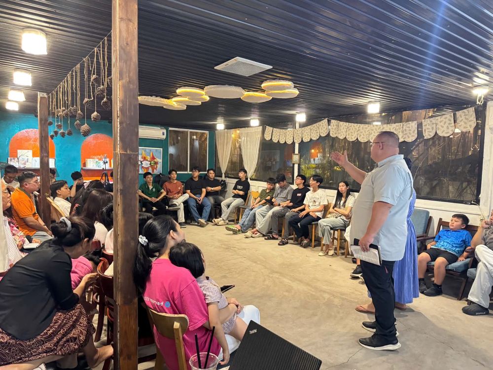 Dr. Shaun preaching to young adults seated around the coffee shop