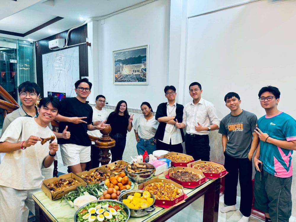 Jonah with young adults around a table of food at the Da Nang ministry house