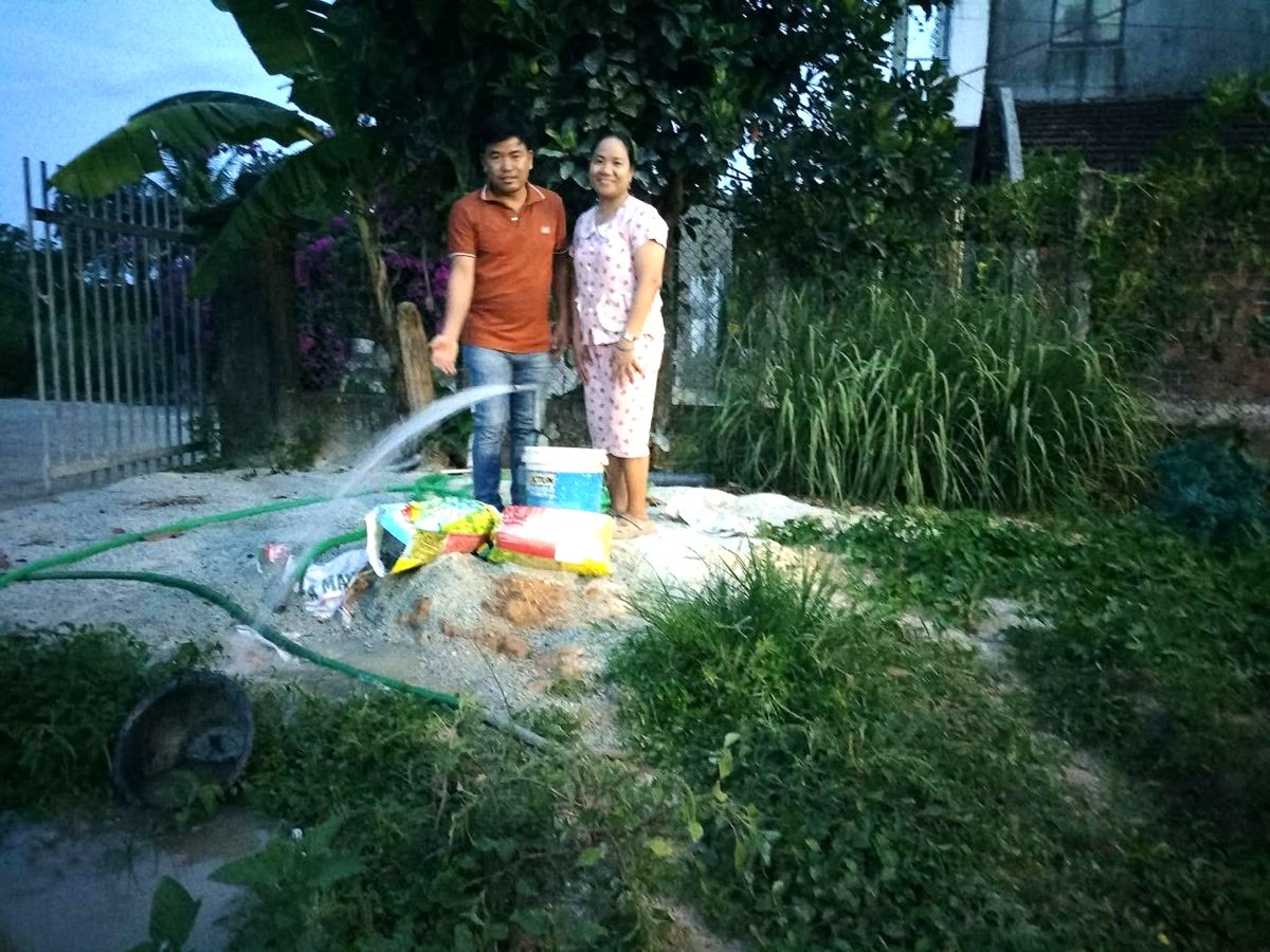 Pastor Quang and his wife beside clean water flowing from the new well