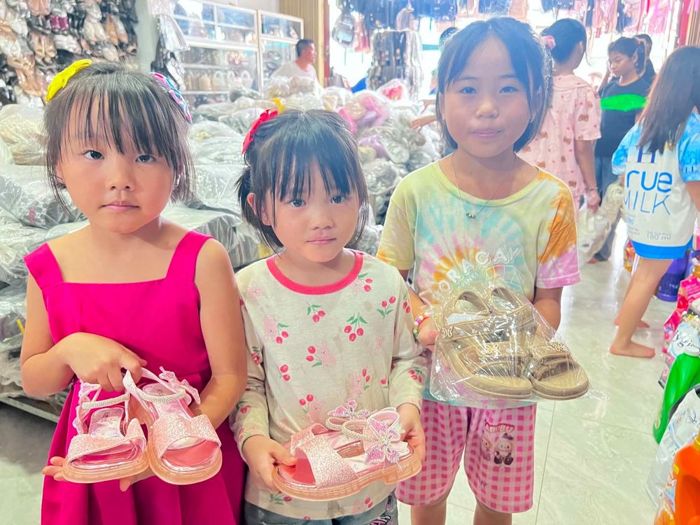 Three girls holding their new shoes