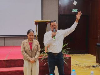 A pastor sharing his testimony with Liên translating