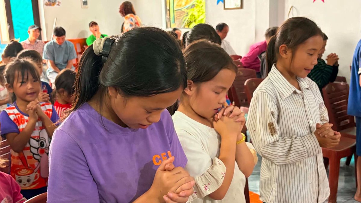 Children praying with hands clasped at a church gathering in Vietnam