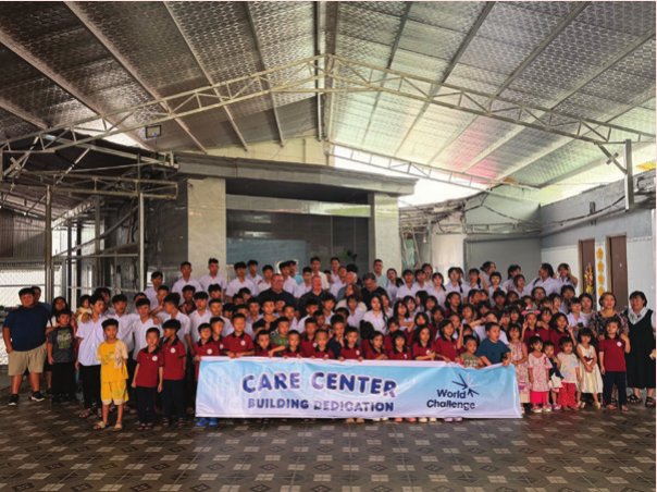 Children and visitors gathered behind a banner at the Care Center building dedication