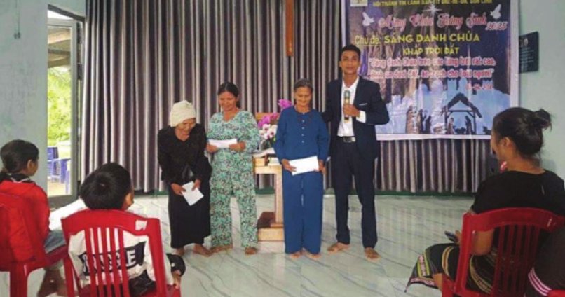 A pastor presenting gifts to women at a church gathering in Quang Ngai