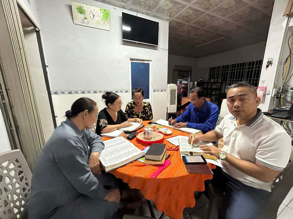 A small group studying the Bible around a table in a home
